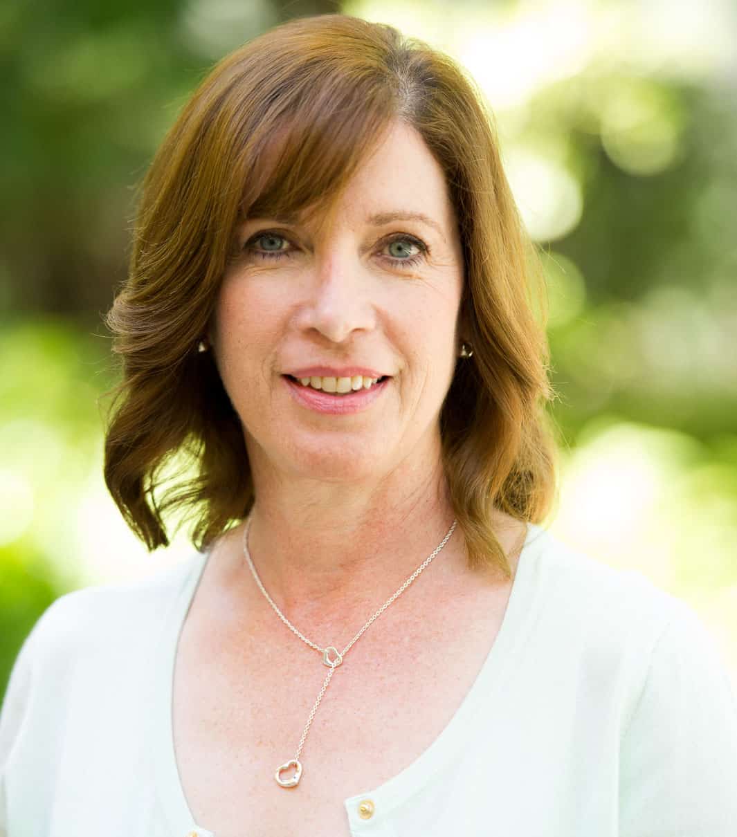 A woman wearing a white shirt and a necklace.