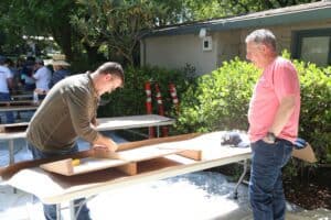 Two men working on a table in a yard.