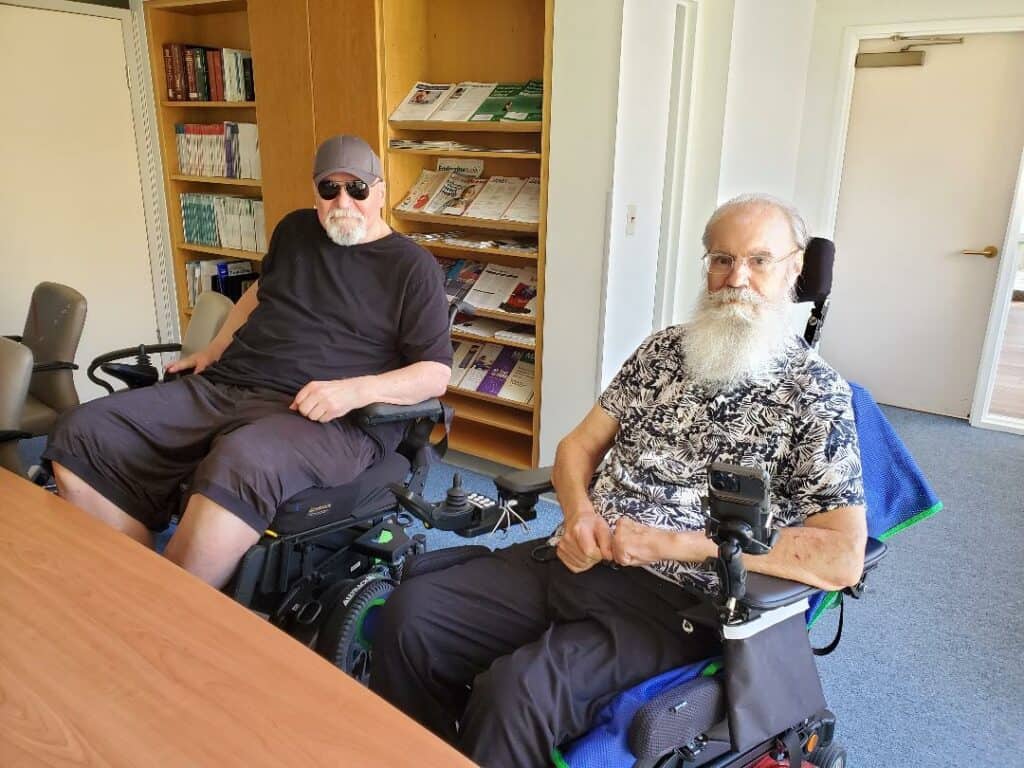 Two men in wheelchairs sitting at a table.