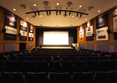 A large auditorium with rows of black chairs.