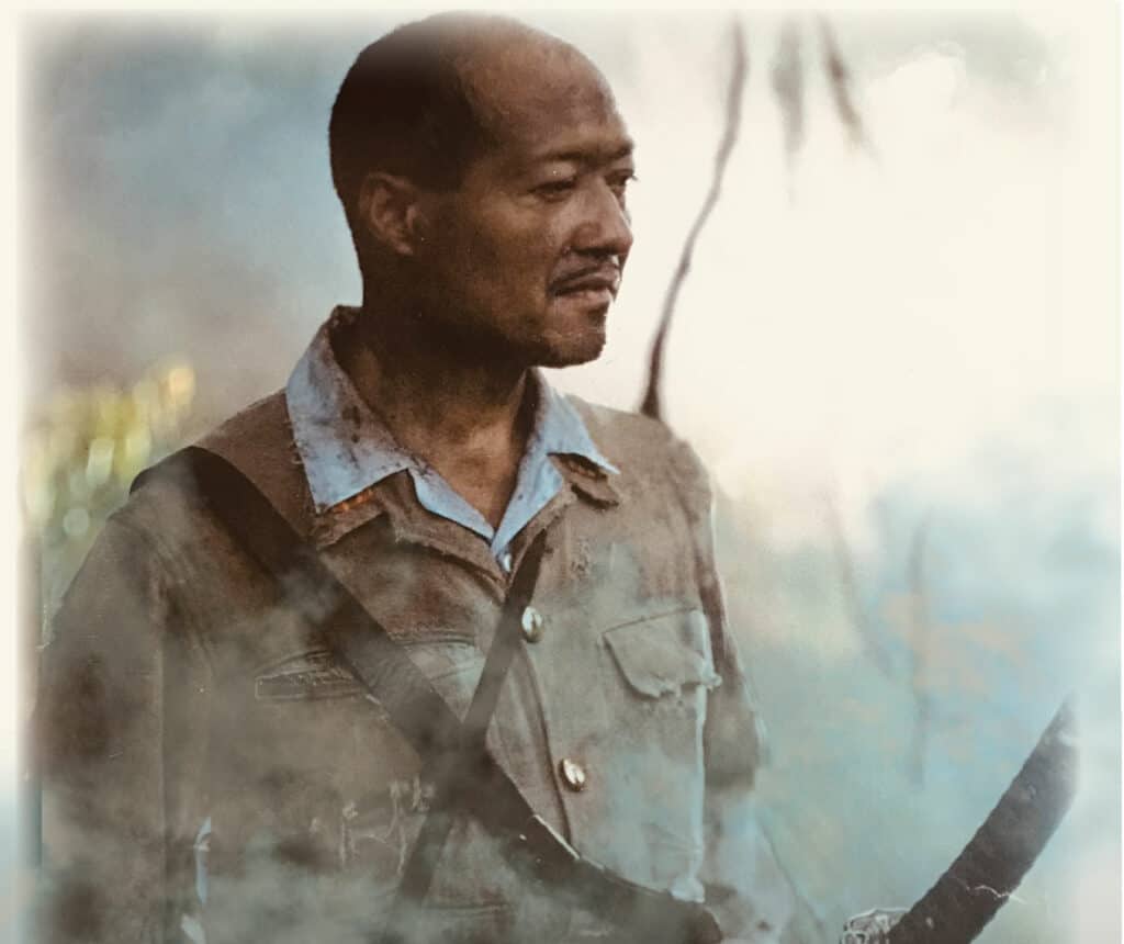 A man holding a gun in front of smoke.