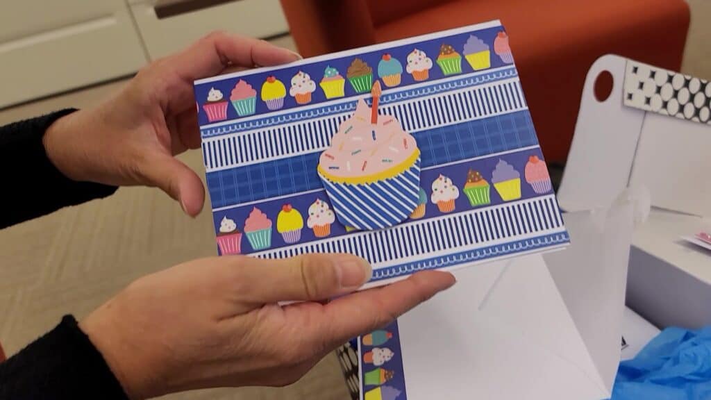 A person holding a card with a cupcake on it.