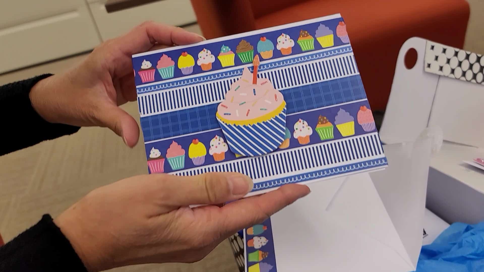 A person holding a card with a cupcake on it.