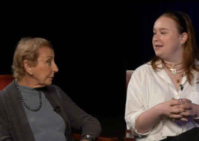 Two women sitting in a chair talking to each other.