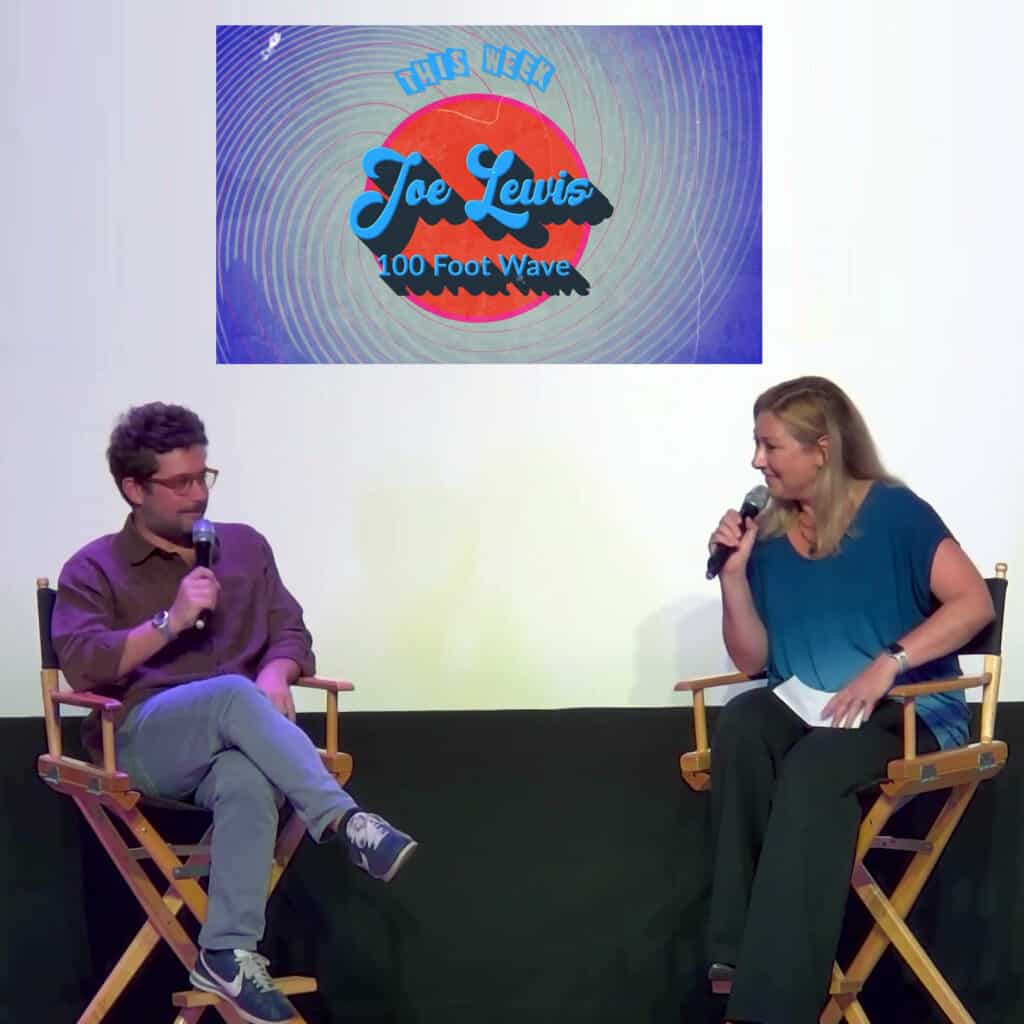 A man and a woman sitting in chairs on a stage.