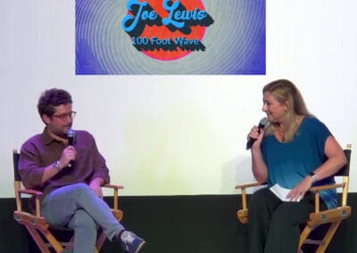 A man and a woman sitting in chairs on a stage.