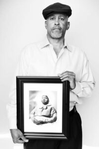 A man holding up a black and white photo of a man.