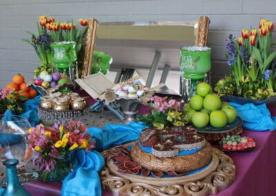 Colorful banquet table with an assortment of fruits, cakes, flowers, and decorative objects.